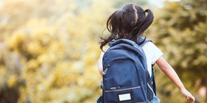 Ενα κορίτσι με σχολική τσάντα και κοτσίδες στα μαλλιά