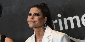 Η Λίσα Ρίνα με λευκό σακάκι χαμογελά