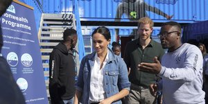 Η Μέγκαν Μαρκλ με τζιν μπουφάν περπατά μπροστά από τον Χάρι