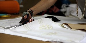 Μοδίστρα κόβει με το ψαλίδι μεταξωτό ύφασμα