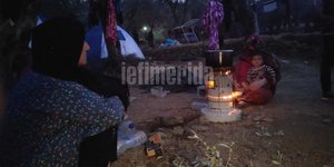 Μετανάστες κάθονται γύρω από τη φωτιά στη Μόρια
