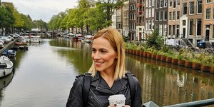 Η Νάντια Μπουλέ με δερμάτινο μπουφάν κρατάει έναν καφέ στο χέρι