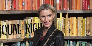 H Νίκι Χίλτον χαμογελάει και φοράει δερμάτινο τζάκετ με πλεξούδες στα μαλλιά