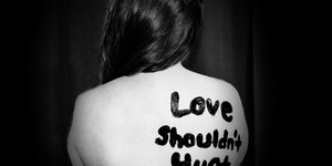 Σύνθημα στην πλάτη γυναίκα που λέει «η αγάπη δεν πρέπει να πονά»
