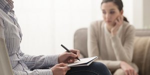 Ψυχολόγος σημειώνει καθώς μια γυναίκα κάθεται σε καρέκλα