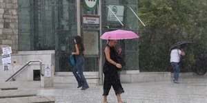 Γυναίκα κρατά ομπρέλα στη βροχή στο Σύνταγμα