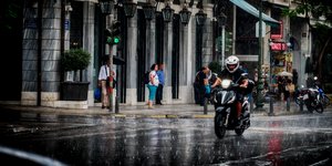 Οδηγός μηχανής σε δρόμο κάτω από βροχή
