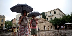 Ζευγάρι με ομπρέλες στη βροχή στην Αθήνα