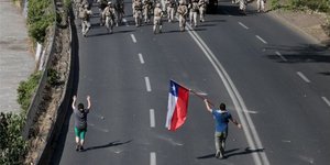 Διαδηλωτής κρατά σημαία απέναντι στον στρατό της Χιλής