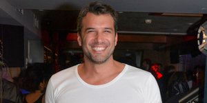 Ο Αντώνης Βλοντάκης με λευκό T-shirt και τζιν χαμογελάει στον φακό 