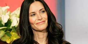 Η Κόρτνεϊ Κοξ με μαύρη μπλούζα χαμογελάει