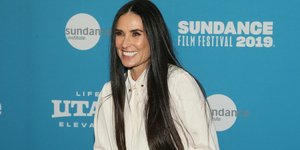 Η Ντέμι Μουρ με λευκό πουκάμισο χαμογελά στο φακό