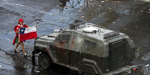 Διαδηλωτής περπατά μπροστά από όχημα του στρατού στη Χιλή