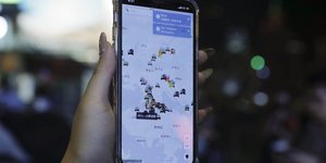 Διαδηλωτής στο Χονγκ Κονγκ κρατά κινητό στο χέρι με την εφαρμογή που κατέβηκε από το Apple Store
