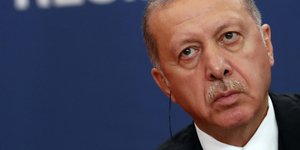 Ερντογάν στο πλάι με μπλε φόντο και κόκκινη σημαία