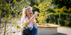 Γυναίκα βγάζει selfie και τρώει ένα γλυκό καθισμένη