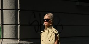 Ξανθιά γυναίκα με μαύρα γυαλιά και μπεζ ολόσωμη φόρμα 