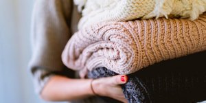 Γυναίκα κρατάει διπλωμένα πουλόβερ στα χέρια