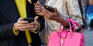 Δύο γυναίκες κρατούν κινητά στο δρόμο 