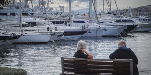 Ηλικιωμένοι σε παγκάκι μπροστά από σκάφη