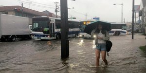 Γυναίκα περπατά με ομπρέλα σε πλημμυρισμένο δρόμο