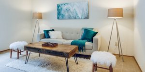 Σαλόνι διαμερίσματος με καναπέ, δύο σκαμπό, χαλί, φωτιστικά και τραπεζάκι