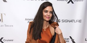 Η Κέιτι Χολμς κρατάει την καμπαρντίνα της και από μέσα φοράει σατέν φόρεμα