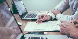 Δύο άνθρωποι κάθονται σε ένα γραφείο και εργάζονται μπροστά από τον υπολογιστή