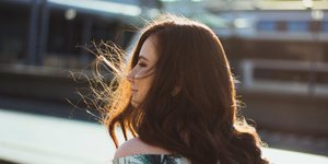 Μελαχρινή κοπέλα βρίσκεται έξω στο δρόμο και ο αέρας κουνάει τα μαλλιά της