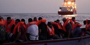 Μετανάστες με σωσίβια σε λέμβο απέναντι σε πλοίο