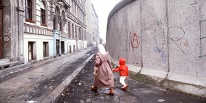 Μητέρα με το παιδί της περπατούν πλάι στο τείχος του Βερολίνου στη Γερμανία