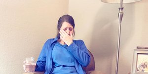 Μια νοσοκόμα με μπλε στολή κάθεται σε δερμάτινη πολυθρόνα και κλαίει