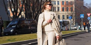 Γυναίκα με παλτό και τσάντα περπατά στον δρόμο