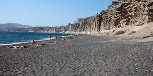 Λουόμενοι σε παραλία της Σαντορίνης κάτω από τον γαλανό ουρανό του Αιγαίου