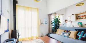 Σαλόνι σπιτιού με κίτρινες κουρτίνες και γκρι καναπέ με ανοιχτή κουζίνα