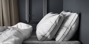 Στρώμα με πάπλωμα και αφράτα μαξιλάρια σε γκρι τοίχο