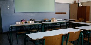 Σχολική αίθουσα ελληνικού σχολείου με θρανία σε σχήμα Π και πράσινο πίνακα