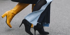 Δυο γυναίκες φορούν κίτρινες μπότες και μαύρες με τζιν παντελόνι