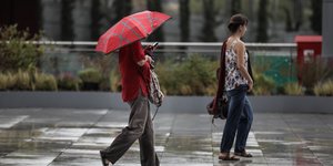 Γυναίκα κρατάει ομπρέλα στη βροχή και περπατάει