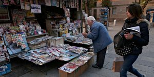Γυναίκα προχωρά δίπλα σε περίπτερο με εφημερίδες