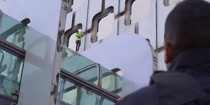 Ο Αλέν Ρομπέρ σκαρφαλώνει σε κτίριο υπό το βλέμμα αστυνομικού