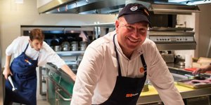 O Εκτορας Μποτρίνι με ποδιά ποζάρει σε κουζίνα