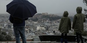 Αντρας με μπλε ομπρέλα στην βροχερή Αθήνα
