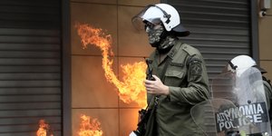 Αστυνομικός των ΜΑΤ και στο βάθος φλόγες από μολότοφ, στο μαθητικό-φοιτητικό συλλαλητήριο