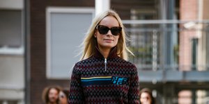 γυναίκα περπατά στην εβδομάδα μόδας με πουλόβερ και γυαλιά