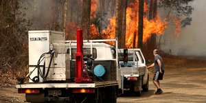 Αυτοκίνητα και άνδρας δίπλα σε φωτιά σε δάσος