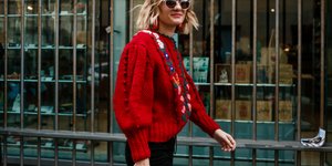 γυναίκα περπατά με πουλόβερ και γυαλιά στο δρόμο