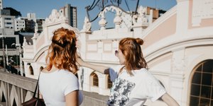 Δύο γυναίκες κοιτούν τη θέα φορώντας φούστες και λευκή μπλούζα
