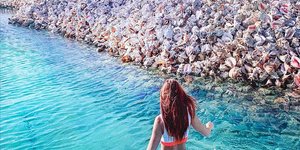 Νησί φτιαγμένο με κοχύλια και κοπέλα κάνει μπάνιο με μπικίνι