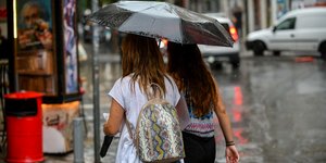 Κοπέλες κρατούν ομπρέλες στη βροχή